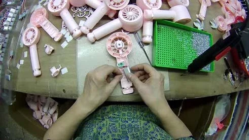 First-person view of hands assembling small electronic parts with a screwdriver